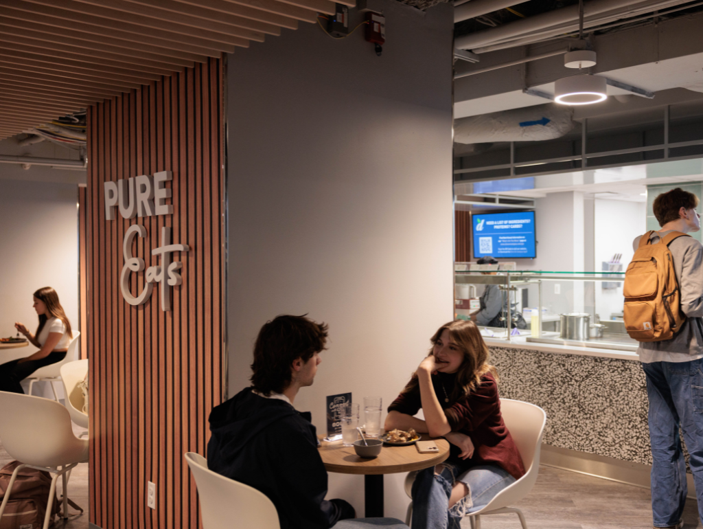 Two students sitting at a table outside the Pure Eats food vendor in Thurston