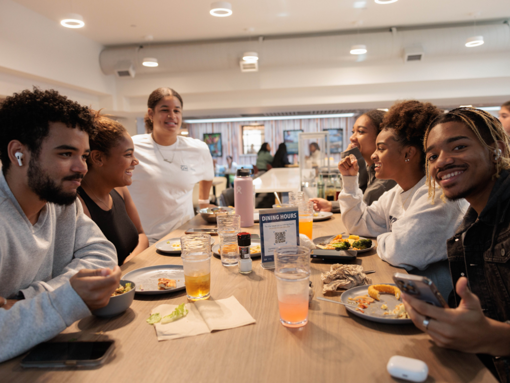 A group of smiling students sitting at a table in the Thurston Dining Hall