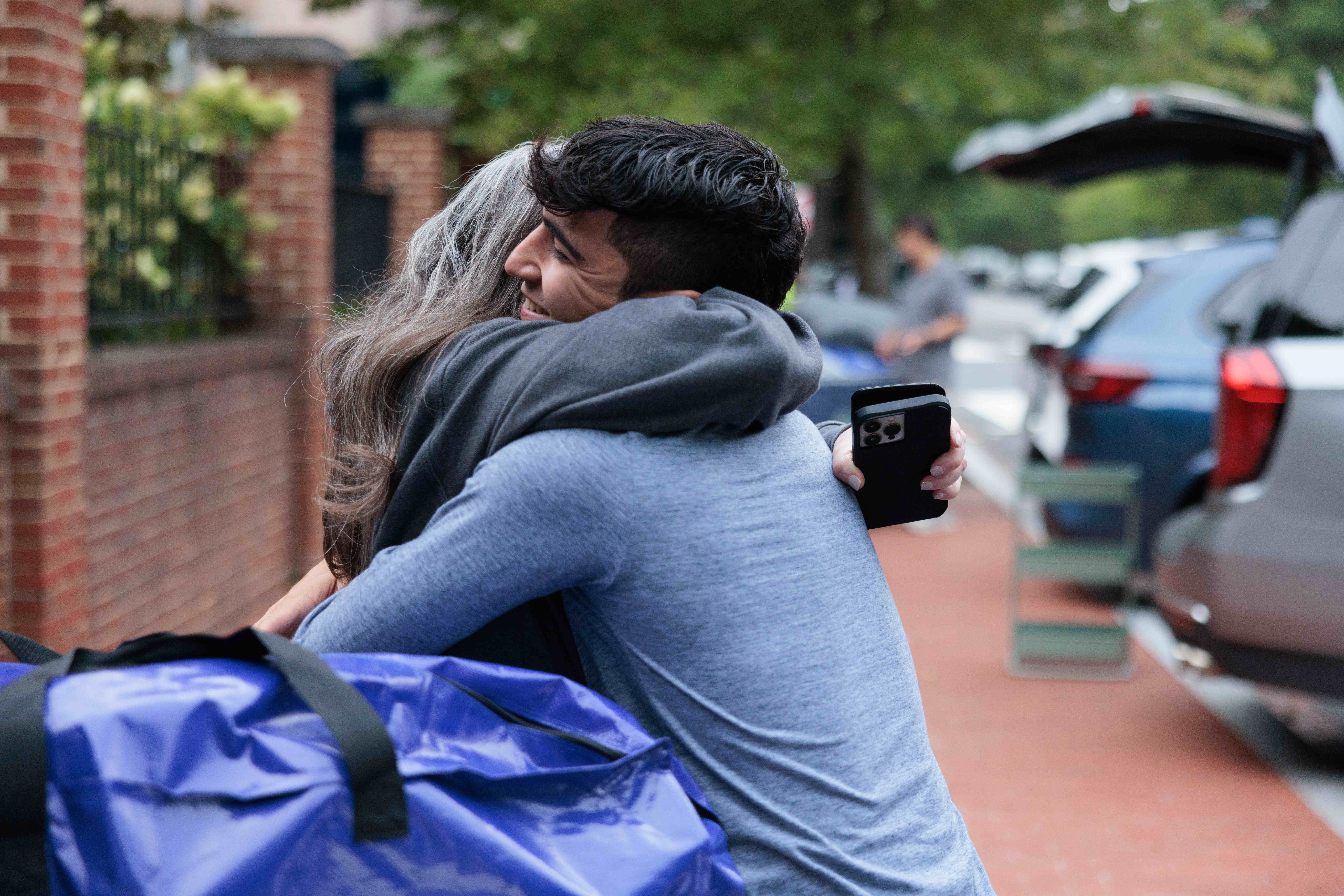 A new student embraces a family member as they being their GW journey