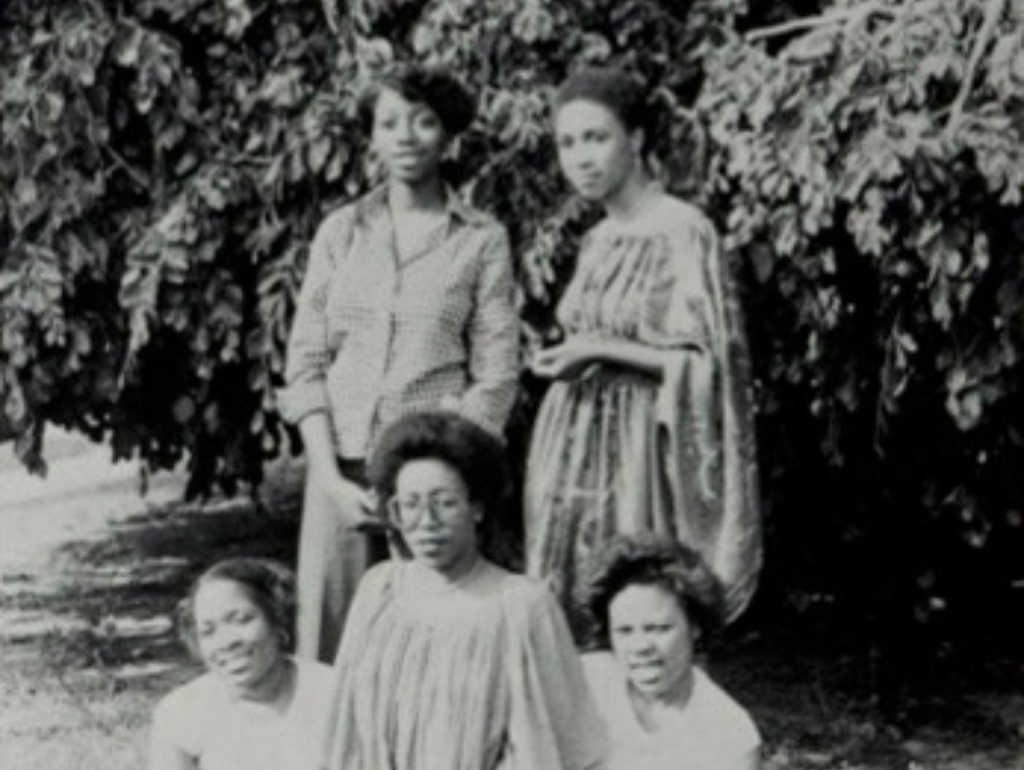 Black and white image of five black women posing for a photo in front of some trees