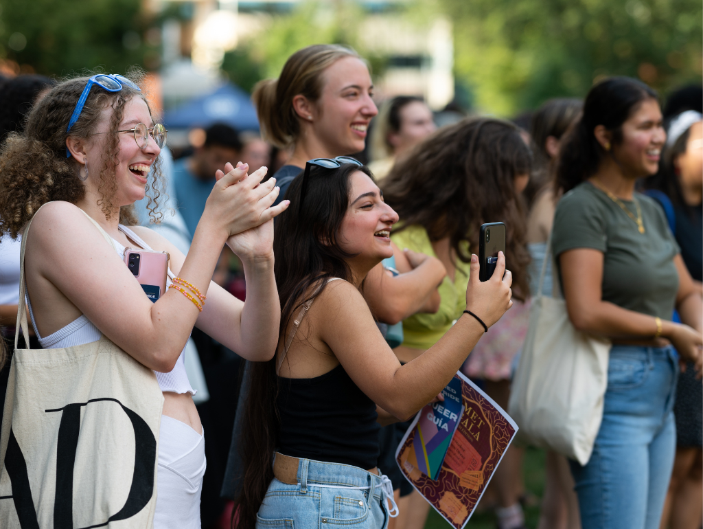Students in a crowd clapping and smiling