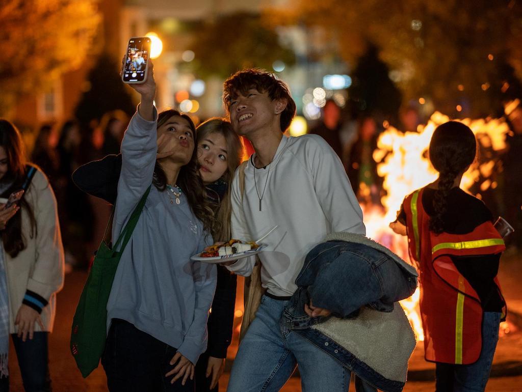 Three students pose for a selfie at the GW Bonfire