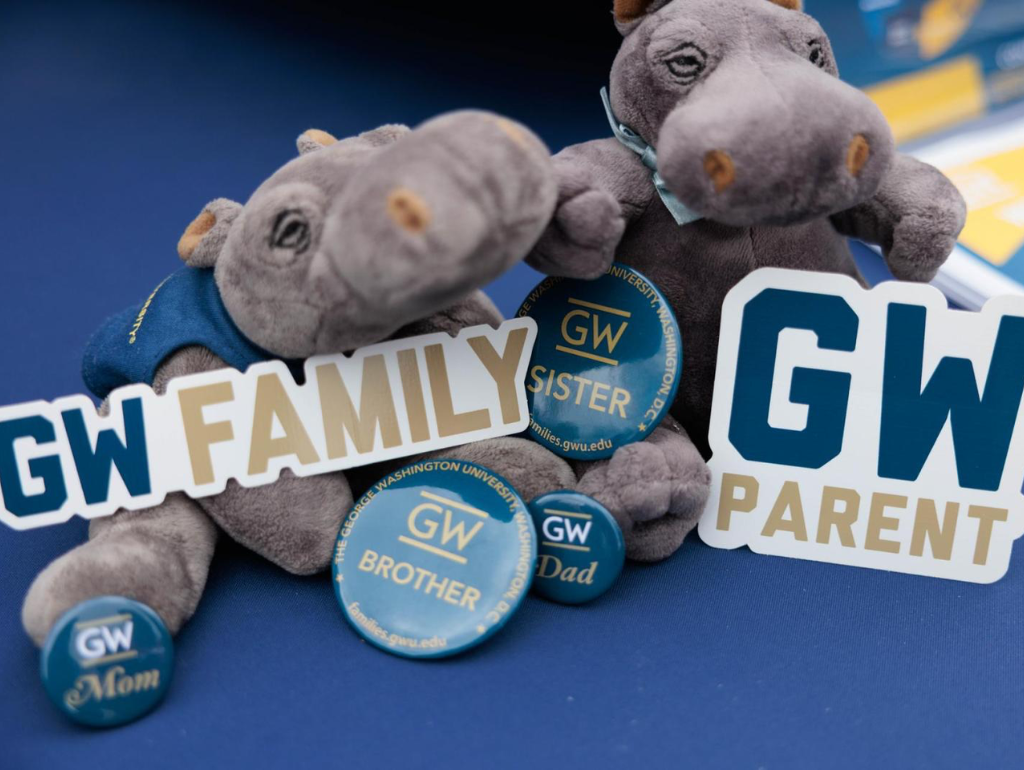 Two small plush hippos surrounded by "GW Families" and "GW Parent" stickers and buttons