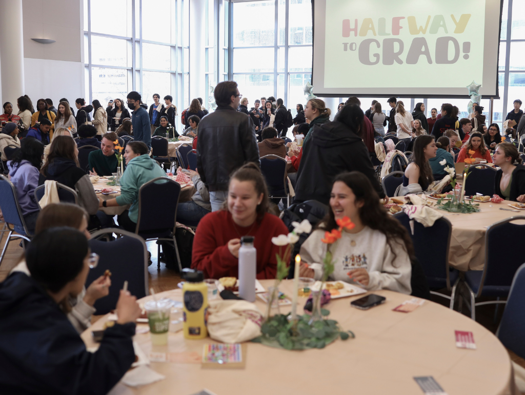 USC Ballroom filled with students, presentation in the background reads "Halfway to Grad"