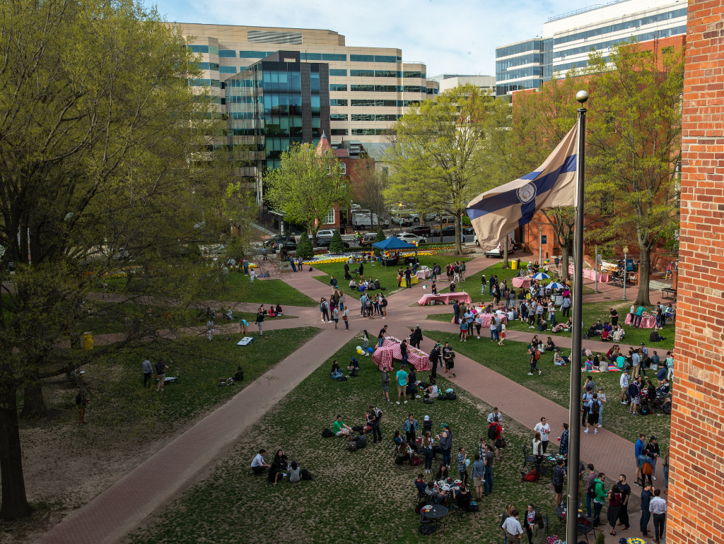 Overhead shot of University Yard set up with tables for an event; people are walking through the Yard, mingling