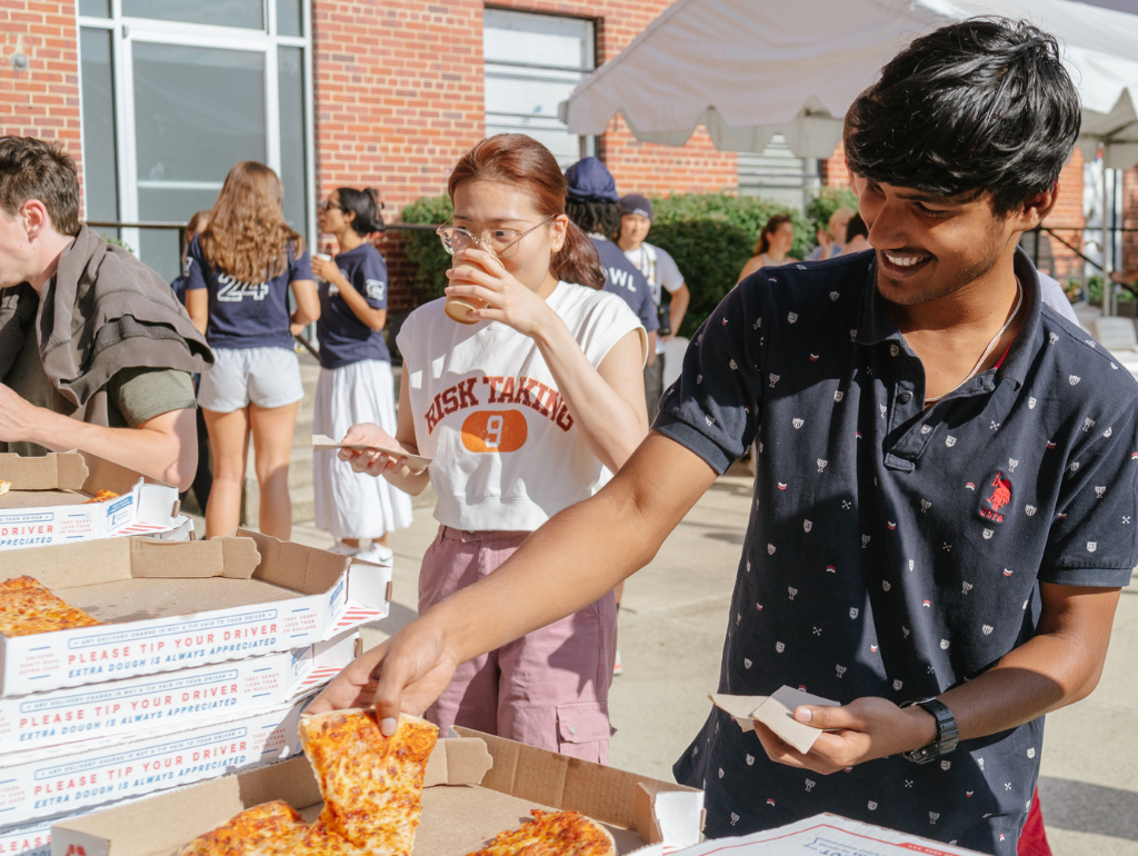 Students taking pizza at the Vern Pool Party