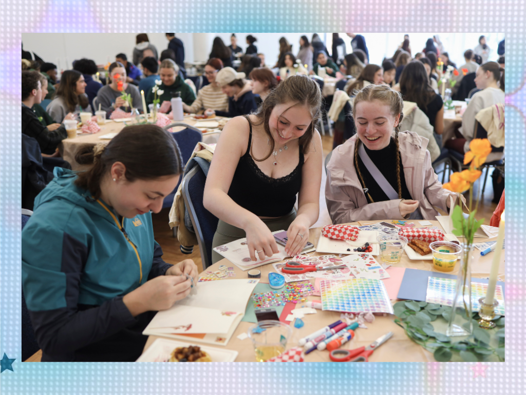 Three students gather around a table to craft