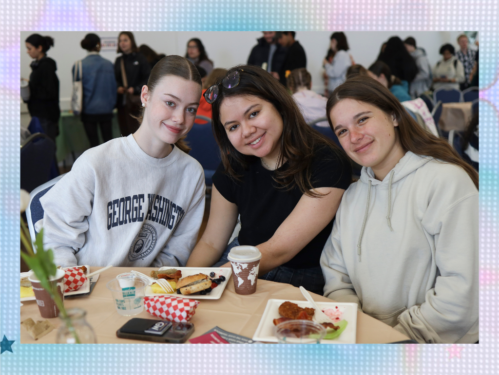 Three students hanging around a table with food