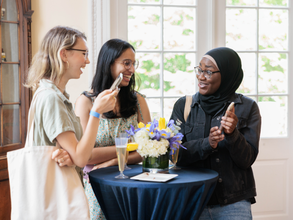 Three senior students in Post Hall smiling at photos, reminiscing at their time on the Vern while at Back to the Vern
