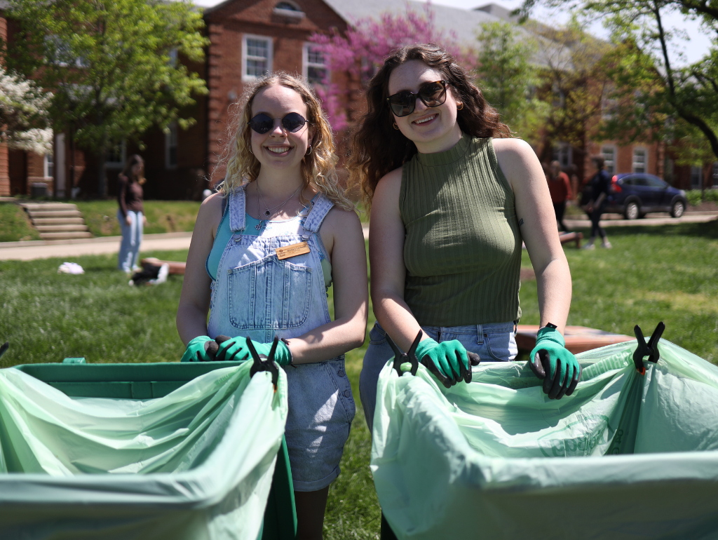 Two students wearing outdoor work gloves collecting compost, trash and recycling on the Vern
