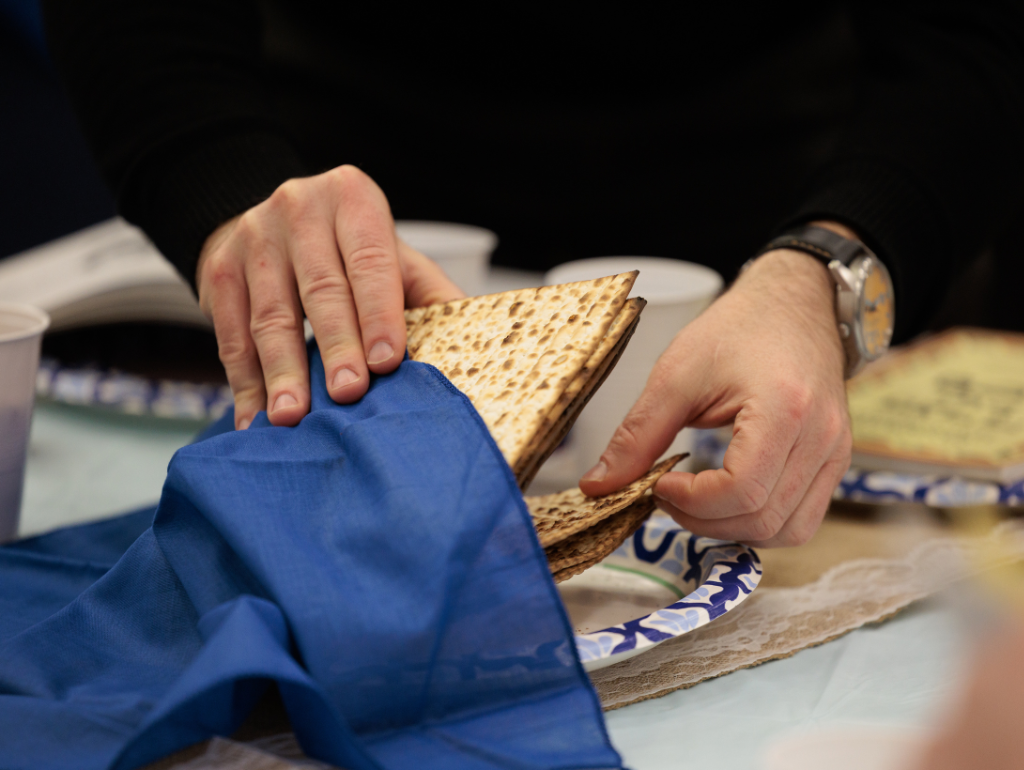 Person reaching for unleavened bread at a GW Passover Seder event.