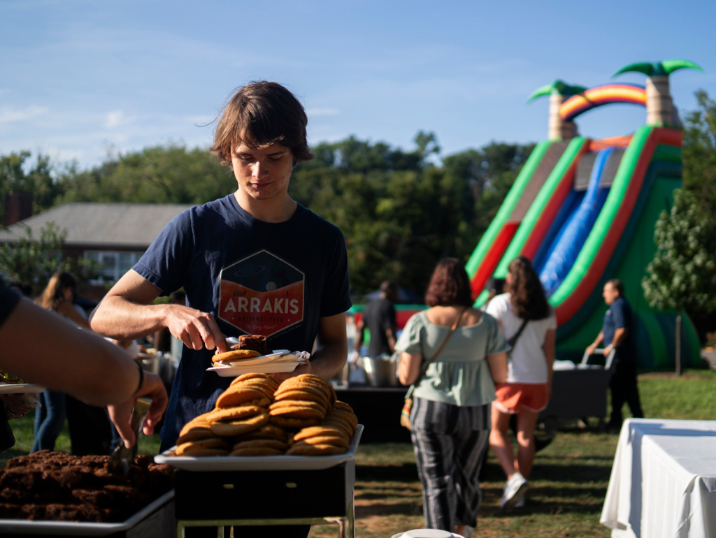 Student getting food at the annual cookout event with a giant inflatable slide in the background