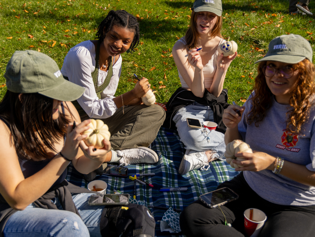 A group of four students sitting on a picnic blanket on the MVC Quad, enjoying food.