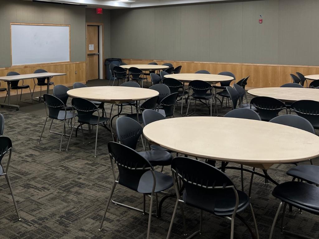 6 round tables with chairs and one long table setup in a carpeted room
